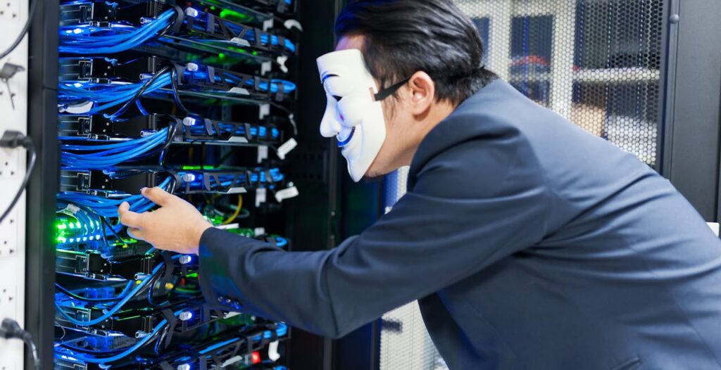 Masked individual interacting with server racks, symbolizing cybersecurity threats.